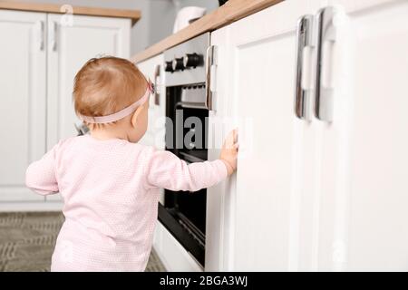 Piccolo bambino vicino stufa in cucina. Bambini in pericolo Foto Stock