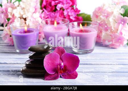 Belle candele colorate, pietre spa e fiori, su sfondo di legno colore Foto Stock