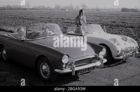 Anni '60, storica, due coppie parcheggiate accanto a un campo vicino a Letchworth Garden città seduta in loro britannici fatto aperto auto sportive top, una Sunbeam Alpine fatto dalla società Rootes e un Austin-Healey Sprite., una piccola roadster. La Sprite, una joint venture tra la Austin Co e Donald Healey, era affettuosamente conosciuta come la "Frogeye" a causa del fatto che i fari erano insolitamente posizionati sul cofano della vettura. Foto Stock