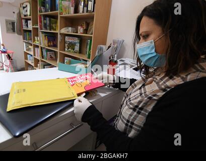 Roma, Italia. 20 aprile 2020. Una donna che indossa una maschera facciale lavora in un negozio di libri per bambini riaperto a Roma, 20 aprile 2020. La pandemia di coronavirus ha causato 24,114 vite in Italia bloccata, poiché per la prima volta le infezioni attive totali sono diminuite da quando la pandemia è scoppiata nelle regioni settentrionali il 21 febbraio, secondo gli ultimi dati pubblicati lunedì dal Dipartimento di protezione civile del Paese. Credit: Alberto Lingria/Xinhua/Alamy Live News Foto Stock