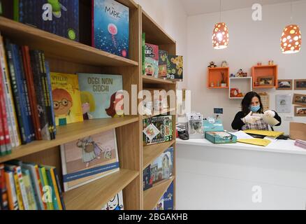 Roma, Italia. 20 aprile 2020. Una donna che indossa una maschera facciale lavora in un negozio di libri per bambini riaperto a Roma, 20 aprile 2020. La pandemia di coronavirus ha causato 24,114 vite in Italia bloccata, poiché per la prima volta le infezioni attive totali sono diminuite da quando la pandemia è scoppiata nelle regioni settentrionali il 21 febbraio, secondo gli ultimi dati pubblicati lunedì dal Dipartimento di protezione civile del Paese. Credit: Alberto Lingria/Xinhua/Alamy Live News Foto Stock