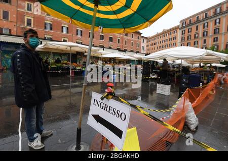 Roma, Italia. 20 aprile 2020. Un uomo che indossa una maschera facciale lavora all'ingresso di un mercato riaperto a Roma, 20 aprile 2020. La pandemia di coronavirus ha causato 24,114 vite in Italia bloccata, poiché per la prima volta le infezioni attive totali sono diminuite da quando la pandemia è scoppiata nelle regioni settentrionali il 21 febbraio, secondo gli ultimi dati pubblicati lunedì dal Dipartimento di protezione civile del Paese. Credit: Alberto Lingria/Xinhua/Alamy Live News Foto Stock