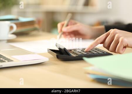 Primo piano di donne imprenditrice mani di calcolo con calcolatrice su una scrivania a casa Foto Stock