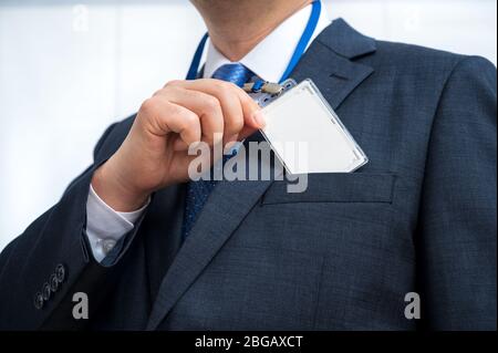 Imprenditore della tuta che indossa un vuoto tag ID o nome scheda su un cordino a una fiera o conferenza Foto Stock