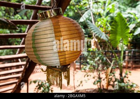 Lampada asiatica nella foresta. Una lampada sferica in una foresta verde. Scale di legno sulla sinistra. Foto Stock