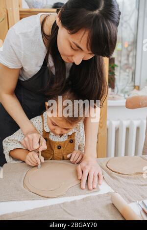 Donna e bambina che taglia fuori il cerchio dal pezzo di argilla arrotolato Foto Stock