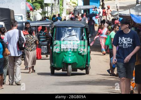 Ella, Sri Lanka. 27 luglio 2016: Tuk-tuk auto rickshaw e turisti e cittadini locali passeggiare per la strada in Ella in Sri Lanka. Foto Stock