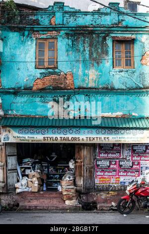 Galle, Sri Lanka. 1 agosto 2016: Vecchio e logoro edificio colorato. Un vecchio edificio in blu chiaro. Business al piano terra. Scena urbana. Foto Stock