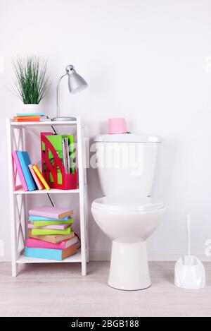 WC bianco e stativo con libri, su sfondo a parete a colori Foto Stock