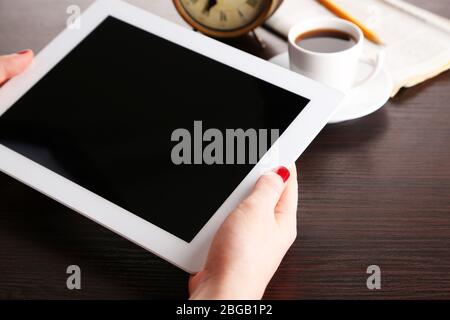 Tavoletta, giornale e tazza di caffè su tavolo di legno Foto Stock