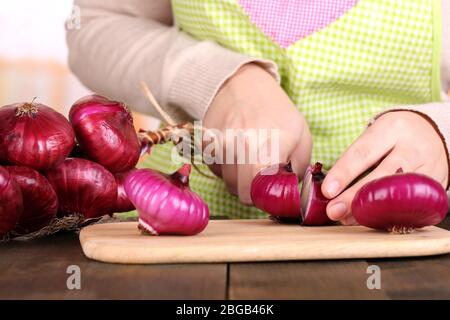 Mani femminili il taglio di Bulbo di cipolla, su sfondo di cucina Foto Stock