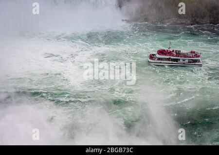 Cascate del Niagara, NY, USA - 13 giugno 2019: Nave con turisti si sposta alle cascate del Niagara, l'esperienza del tour in barca delle cascate è l'attrazione più antica del Nord America, e. Foto Stock