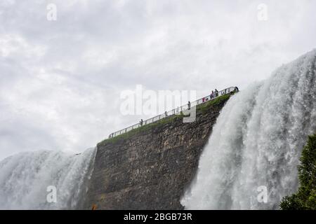 Cascate del Niagara, NY, USA - 13 giugno 2019: I visitatori della piattaforma di osservazione sopra la caduta americana, vista dal basso Foto Stock