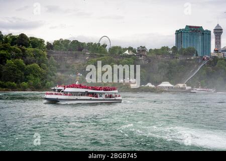 Cascate del Niagara, NY, USA - 13 giugno 2019: Nave con turisti si sposta alle cascate del Niagara, l'esperienza del tour in barca delle cascate è l'attrazione più antica del Nord America, e. Foto Stock