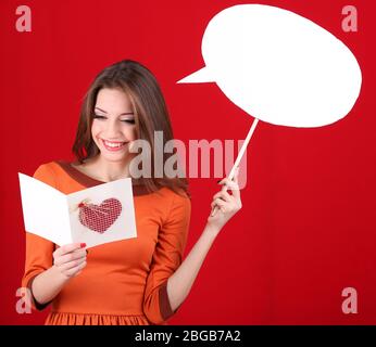 Donna attraente con cartolina, su sfondo rosso Foto Stock