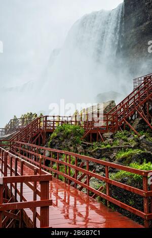 Cascate del Niagara, NY, USA - 13 giugno 2019: I visitatori in impermeabili su scale di legno bagnate fanno un tour sotto gli schizzi delle cascate americane Foto Stock