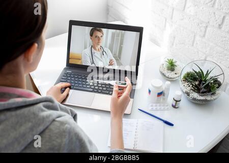 Una donna con una febbre alta ha avuto l'influenza, una consultazione online con il suo medico terapeuta. tecnologia medica, video chat con un medico Foto Stock