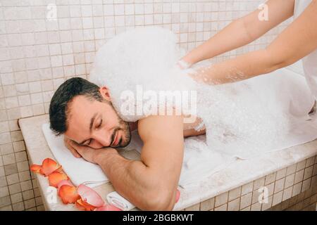 Relax di lusso uomo orientale in bagno turco. L'operatore dell'hammam lava la pelle degli uomini nell'hammam Foto Stock