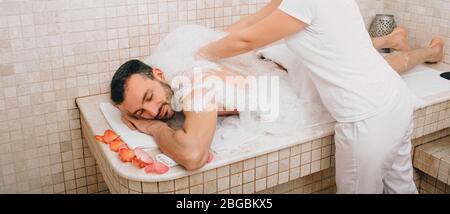 Relax di lusso uomo orientale in bagno turco. L'operatore dell'hammam lava la pelle degli uomini nell'hammam Foto Stock