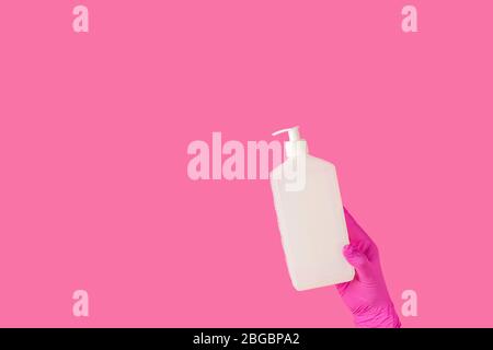 Il medico tiene il gel igienizzante nelle mani guanti medici rosa su una superficie rosa. Virus della corona pandemica, assicurazioni, malattie trasmesse dall'aria, SARS, grippe Foto Stock