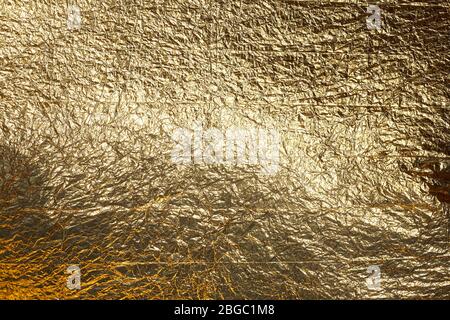 Trama di un foglio sottile di foglio di carta stropicciato. Sfondo in lamina sminuzzata. Lamina fotografica di scorta. Colore oro cromo. Foto Stock