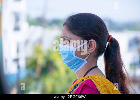 Primo piano di una maschera medica coronavirus indossata da una giovane donna indiana - influenza vista laterale, SARS, Covid 19, protezione contro il virus Foto Stock