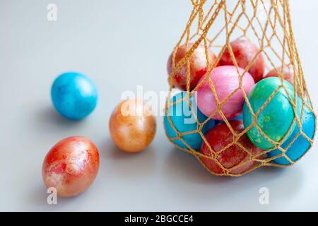 Diverse uova a coste in un sacchetto a maglia. Tre uova giacciono nelle vicinanze su uno sfondo bianco. Spazio di copia Foto Stock