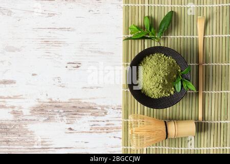 Polvere di tè matcha verde e accessori per il tè su sfondo bianco vista dall'alto. Concetto di ricetta giapponese del tè. Cucchiaio Chashaku e whisky di bambù chasen f Foto Stock