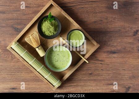Tè e tè matcha verde biologico e accessori sul vassoio su tavolo in legno vista. Cerimonia del tè giapponese. Alimentazione sana, disintossicazione. Foto Stock