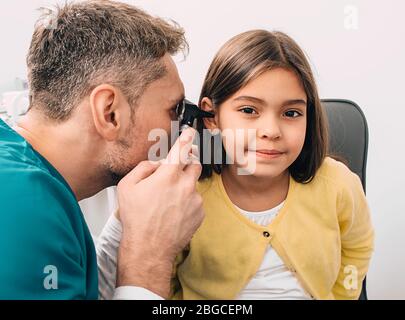 Esame auricolare. Pediatra esame piccolo bambino di razza mista con otoscopio, esame uditivo del bambino Foto Stock