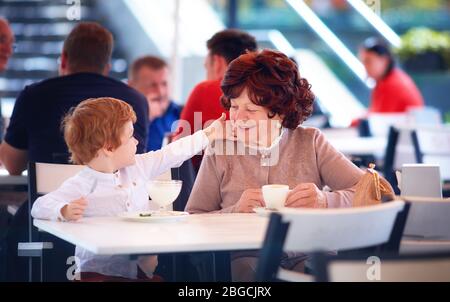 buona nonna divertendosi, seduti in un caffè estivo con il suo grande nipote, dolci prelibatezze Foto Stock