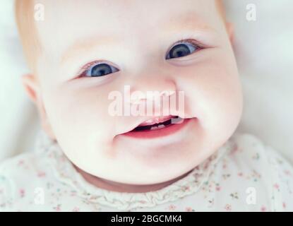 vista superiore della bambina del bambino, smilyng con i suoi primi due denti Foto Stock