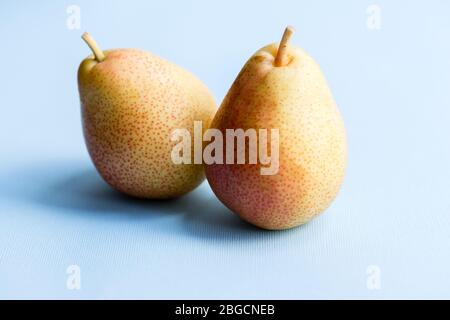Due pere gialle su sfondo azzurro. Frutta dieta vegana. Foto Stock