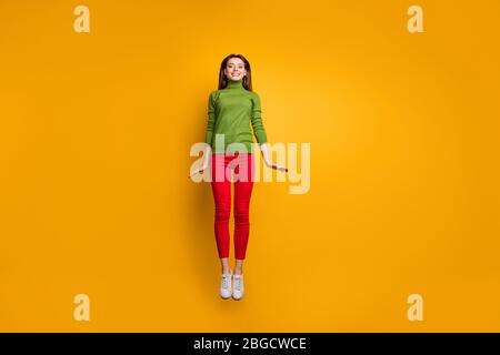 Foto corpo pieno di ragazza allegra positiva hanno tempo libero salto emozioni candid indossare abbigliamento casual stile isolato su sfondo colore giallo Foto Stock