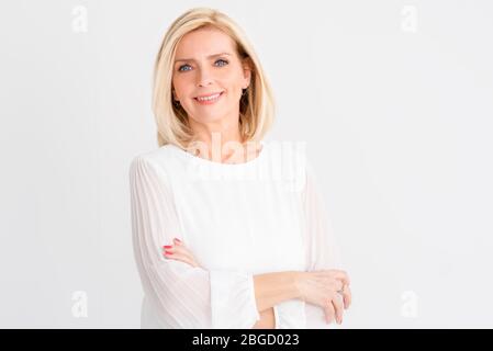 Testa di bella donna anziana guardando la macchina fotografica e sorridente mentre si trova su sfondo bianco isolato. Foto Stock