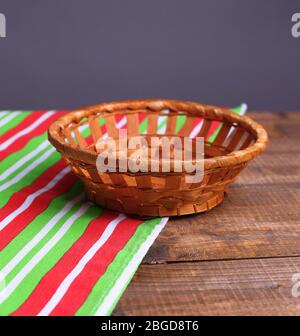 Cesto di vimini vuoto su tavolo di legno, su sfondo scuro Foto Stock