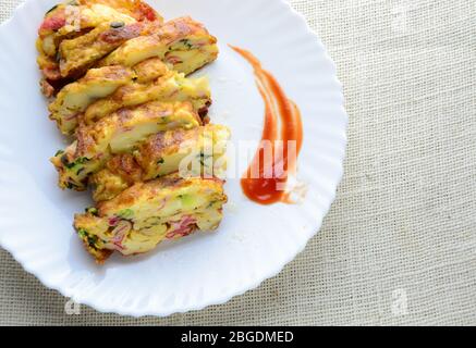 Frittata a fette con tofu morbido, bastone di granchio e cipolla di primavera con riso sul piatto Foto Stock