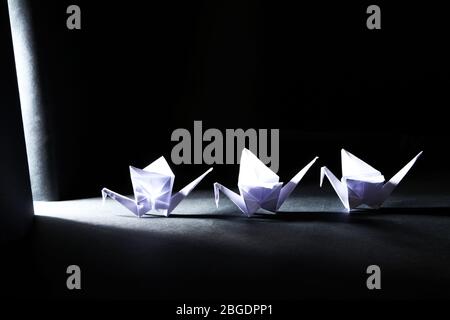 Origami gru su fondo scuro con luce Foto Stock