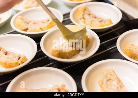 Un classico tradizionale dessert della scuola britannica, Jam Roly-Poly, servito presso un'organizzazione di cibo della comunità in un municipio Foto Stock
