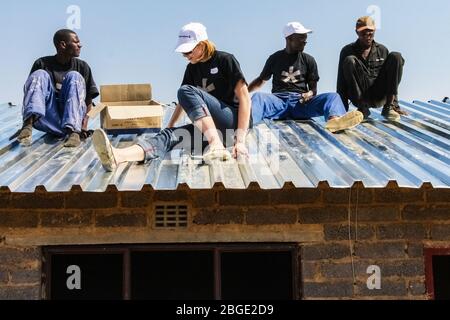 Soweto, Sudafrica - 05 settembre 2009: Programma diversificato di Comunità di Outreach che aiuta ad installare tetto di metallo su una piccola casa a prezzi accessibili in locale a. Foto Stock