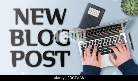 Blog e creazione di contenuti concetto, testo NUOVO POST BLOG contro la scrivania con persona che lavora sul computer portatile Foto Stock
