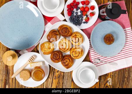 prima colazione nel villaggio panini freschi, caffè, frutti di bosco e miele disposti su un vecchio tavolo di legno marrone Foto Stock