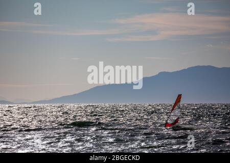 Ventoso pomeriggio inverno profilo windsurf nel mare di Tracia, paesaggio marino, sport acquatici divertimento, sport, attività, vacanza e concetto di viaggio. Grecia settentrionale vicino al villaggio di Porto Lagos Foto Stock