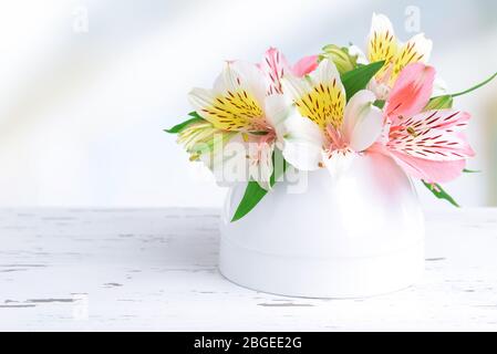 Fiori in vaso su tavolo su sfondo chiaro Foto Stock