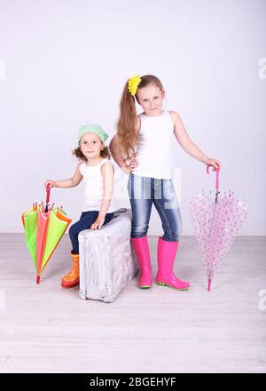 Belle ragazze piccole con valigia su sfondo chiaro Foto Stock