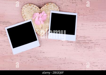 Vecchie foto vuote e cuore decorativo su sfondo legno colore Foto Stock