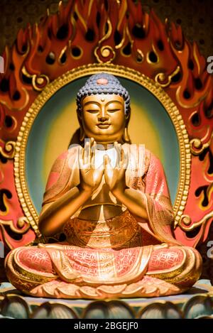Singapore, ottobre 2019: Statua dorata del Buddha seduta in meditazione sul fiore di loto. All'interno del Tempio Reliquico del dente del Buddha, Chinatown Foto Stock