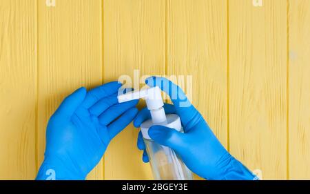 Flacone igienizzante per le mani in guanti primo piano. Richiedere la disinfezione delle mani. Stop concetto di coronavirus. Uso di gel antibatterico per le mani durante Foto Stock