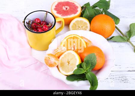 Frutta fresca con foglie verdi in ciotola su sfondo di legno Foto Stock