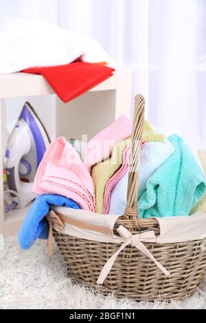Asciugamani colorati in cesto su sfondo interno casa Foto Stock
